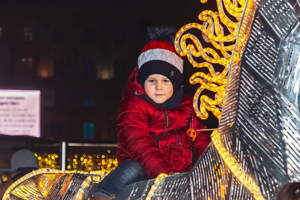 30 Aralık 2018 Minsk Belarus Yeni Yıl kutlamaları şehir meydanında. Küçük bir çocuk yürüyen insanlar arasında yeni yıl tatili sırasında meydanda parlayan bir at üzerinde oturur