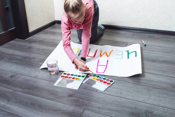 Genç kız yere resim çiziyor. Kağıda boyalar çiziyor. — Stok fotoğraf