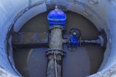 Boru hattı elemanları, plastik borular, beton kuyuda dökme demir vana. Boruda beton bir durak var. Yakın çekim