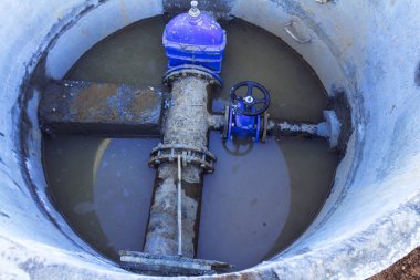 Boru hattı elemanları, plastik borular, beton kuyuda dökme demir vana. Boruda beton bir durak var..