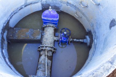 Boru hattı elemanları, plastik borular, beton kuyuda dökme demir vana. Boruda beton bir durak var. Beton kuyuda yağmur suyu