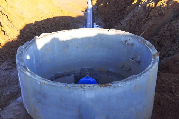 Pipeline elements, plastic pipes, cast-iron valve in a concrete well. Plastic pipe coming out of concrete ring