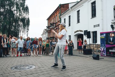 21 Temmuz 2018 , Minsk,Belarus Caddesi parlak giysiler içinde güzel kız yürüyor bir mikrofon şarkı ve insanların önünde bir sokak konserinde dans ediyor