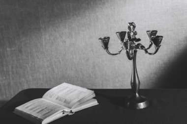 Eski bir mum çubuğu yaslanmış bir kitabın yanında karanlıkta duruyor..