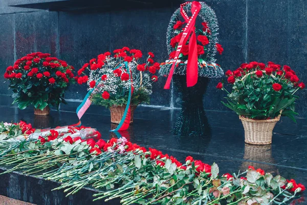 Paniers de fleurs sont à côté des fleurs éparses au monument — Photo