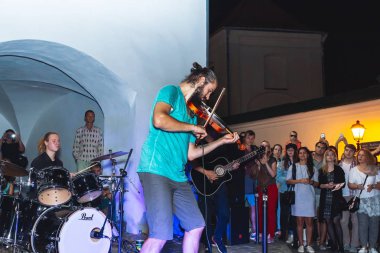 1 Eylül 2018 Minsk Belarus Caddesi şenlikleri akşam şehrinde bir sokak konserinde sakallı genç bir adam insanların önünde keman çalıyor