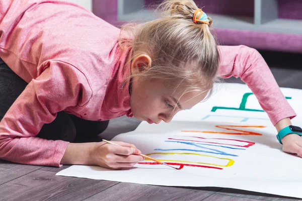 Genç kız yere resim çiziyor. Kağıda boyalar çiziyor. — Stok fotoğraf