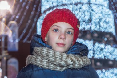 Genç bir güzel kız onu aydınlatma çelenk hakkında farklı ortasında sokakta duruyor