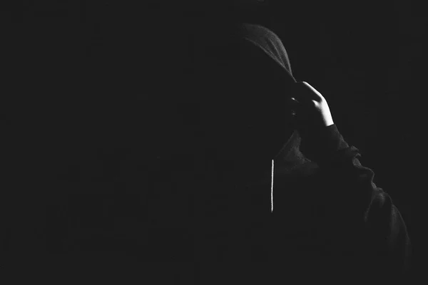 Wütender Mann steht im Dunkeln in einer Kapuze. — Stockfoto
