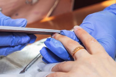 28 Nisan 2019, Minsk Belarus Manikürcüsü evde manikür için tırnak törpüsü kullanıyor.