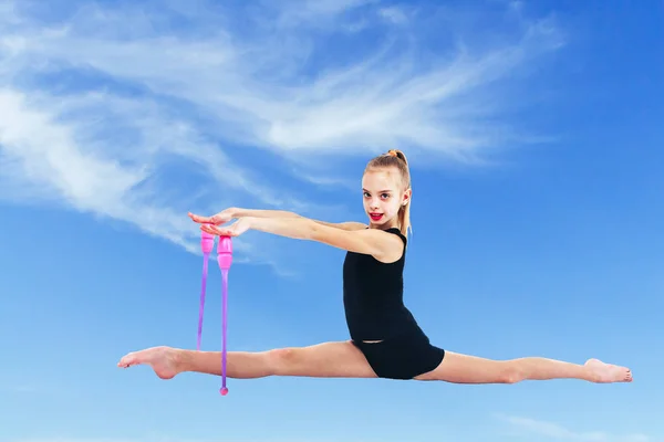 Молодая гимнастка сидит в струнных булавах для гимнастики — стоковое фото