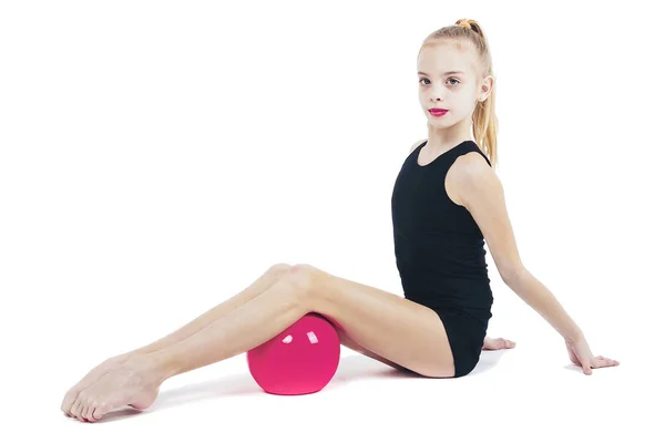 Молода дівчина гімнастка сидить з червоним м'ячем — стокове фото