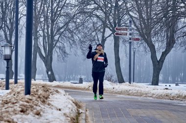 9 Şubat 2019 Minsk Belarus Koşusu 14 Şubat 'a adanmıştır. Elini kaldırmış mutlu bir adam kışın parkta bir yolda koşar.