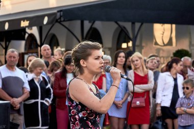 25 Mayıs 2019 'da Minsk Belarus' ta genç beyaz bir kadının bir grup insanın önünde mikrofonla şarkı söylediği bir tiyatro gösterisi.