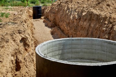 Concrete wells covered with waterproof mastic in a pipe-laying trench