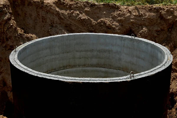 Close-up of a concrete well covered with waterproof mastic in a pipe-laying trench