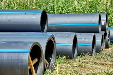 Çapı korumak için ahşap destekli soğuk su tedariği için polietilen basınç boruları kurulmadan önce çimenlerin üzerinde yatar.