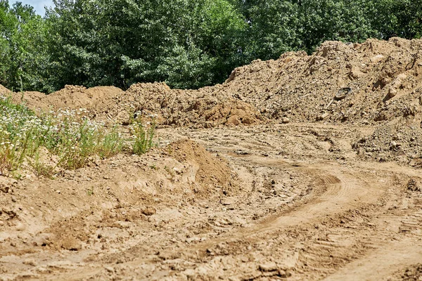 Toprak yığınının ortasında inşaat malzemesi izleri olan bir yol.