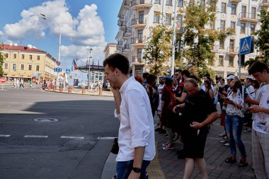 16 Ağustos 2020, Minsk Belarus. Yolun karşısındaki insanlar arasında genç bir adam telefon görüşmesi yapıyor.