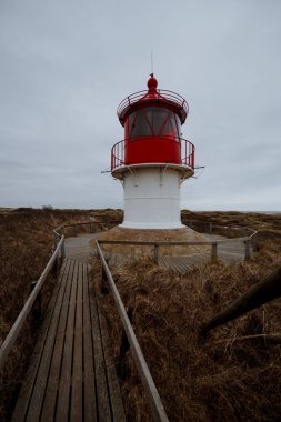 Bulutlu pastoral manzara bir tepenin üstünde kırmızı deniz feneri