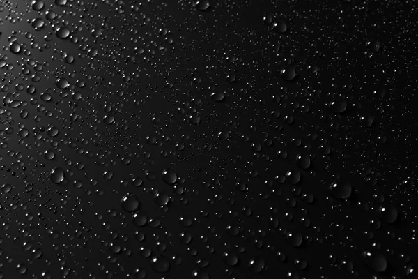 Vidro com gotas de chuva contra fundo escuro — Fotografia de Stock
