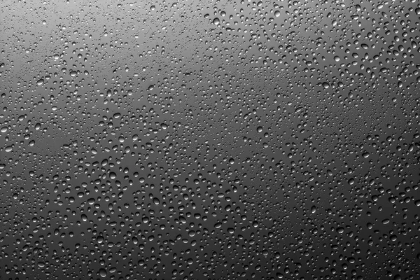 Water droplets on a translucent black glass background with grad — ストック写真