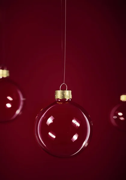 Glas jul bollar hängande framför mörkröd bakgrund — Stockfoto