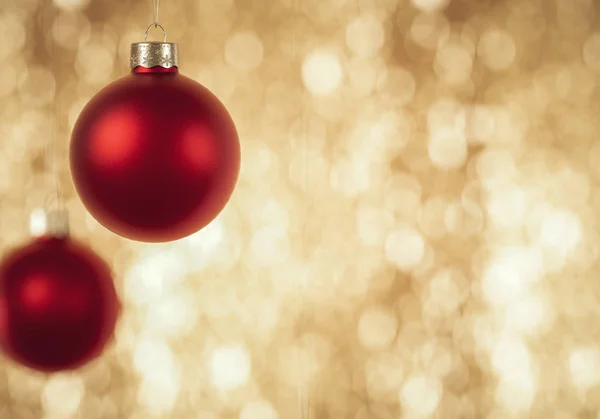 Red Christmas Baubles appeso davanti al lucido dorso in oro bokeh Immagini Stock Royalty Free