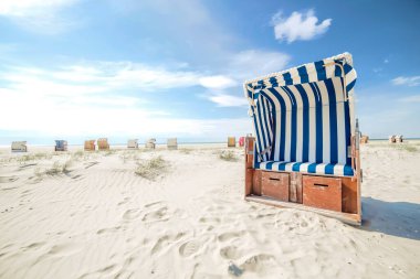 Sıcak bir yaz gününde mavi ve beyaz çizgili hasır sandalye ya da beyaz kumlu boş bir plajda bank. Corona virüsü yayıldıktan sonra tatil gezisi ya da terk edilmiş plaj konsepti.