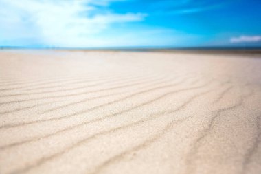 Terk edilmiş beyaz kumsalda sakin bir gün. Su dalgaları tarafından yapılan renk çizgilerinin düşük açılı görüntüsü. Yaz tatili kavramı. Sığ alan derinliği.