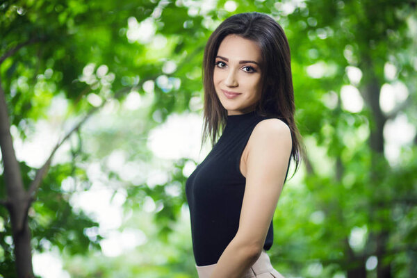 Young beauty girl posing in city park near the beautiful wooden handrails