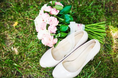 Kadın moda düğün ayakkabıları ile yeşil çim zemin üzerine pastel tonlarda zarif gelin buketi. Düğün detayları.