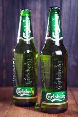 Kiev, Ukrayna - 05 Temmuz 2018: Carlsberg şişe bira ahşap arka plan üzerinde. Danimarkalı bira şirketi 1847 yılında kurulmuştur.
