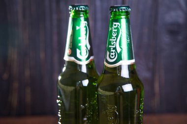 Kiev, Ukrayna - 05 Temmuz 2018: Carlsberg şişe bira ahşap arka plan üzerinde. Danimarkalı bira şirketi 1847 yılında kurulmuştur.