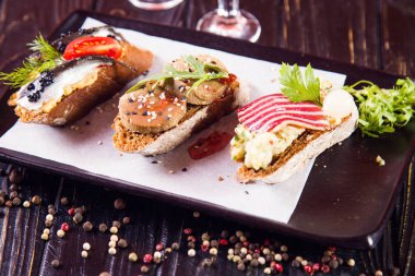 Bruschetta ringa balığı, ezme ve siyah ahşap arka plan üzerinde et ile
