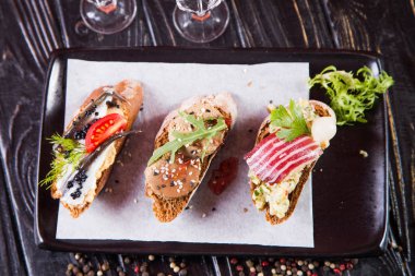 Bruschetta ringa balığı, ezme ve siyah ahşap arka plan üzerinde et ile