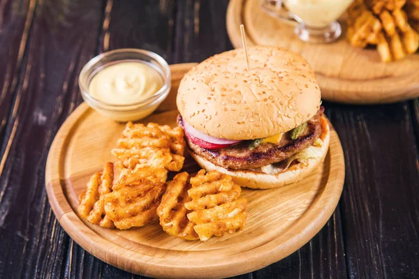 hot fresh burger with potato chips and mustard on wooden background