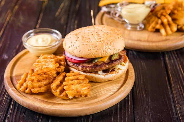 hot fresh burger with potato chips and mustard on wooden background