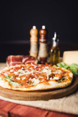 sıcak taze pizza zekâ peynir, jambon ve fesleğen ahşap plaka üzerinde