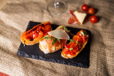 Bruschetta jambon, parmesan ve sebze. Bruschetta siyah plaka üzerinde