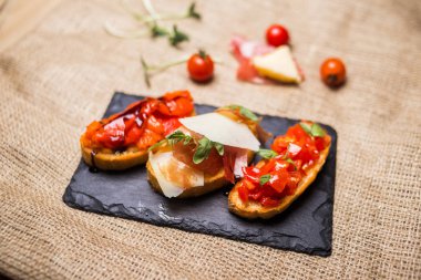 Bruschetta jambon, parmesan ve sebze. Bruschetta siyah plaka üzerinde