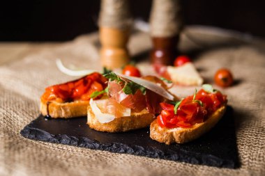 Bruschetta jambon, parmesan ve sebze. Bruschetta siyah plaka üzerinde