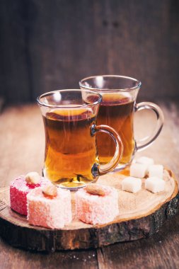 ahşap arka plan üzerinde renkli Türk lokumu ile çay bardak