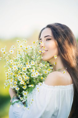 Dışarıda, çayırda elinde buketle güzel bir genç kızın portresi.