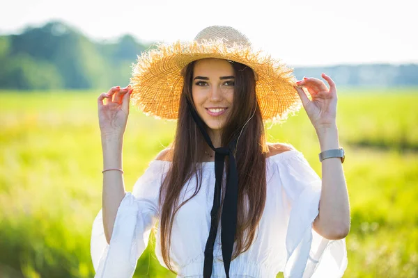 一个戴着帽子 戴着花束 站在户外田野里的漂亮姑娘的画像 — 图库照片