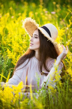 Genç, güzel Avrupalı kız batan güneşte, tarlada, şapkalı