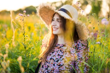 Genç, güzel Avrupalı kız batan güneşte, tarlada, şapkalı