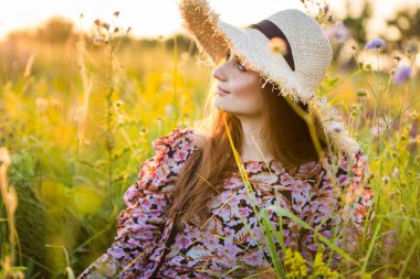 Genç, güzel Avrupalı kız batan güneşte, tarlada, şapkalı