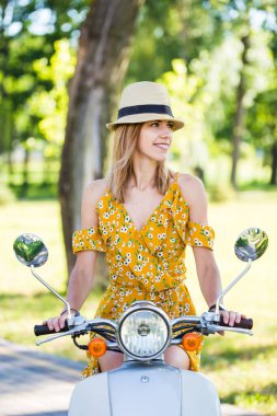Sarı elbiseli güzel Avrupalı kız sabah parkında scooterlı.
