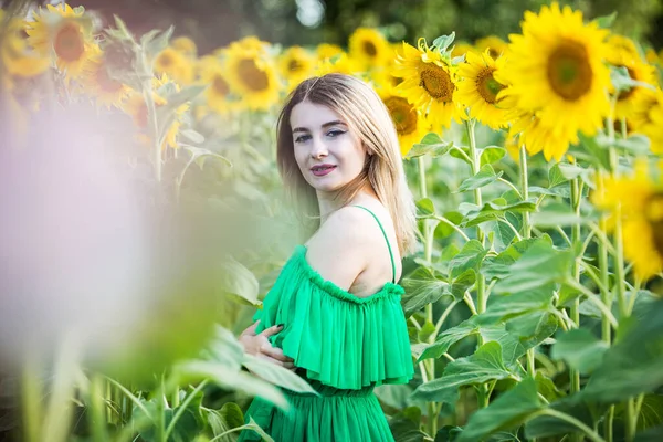 ブロンドヨーロッパの女の子で緑のドレスにひまわり — ストック写真